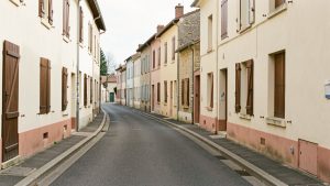 Vue réaliste d’une rue résidentielle de Tonneins bordée de maisons de ville, avec plusieurs volets fermés et une lumière naturelle douce.