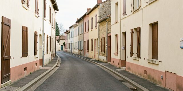 Vue réaliste d’une rue résidentielle de Tonneins bordée de maisons de ville, avec plusieurs volets fermés et une lumière naturelle douce.