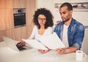 Deux associés examinent des documents immobiliers autour d’une table avant un achat à plusieurs.