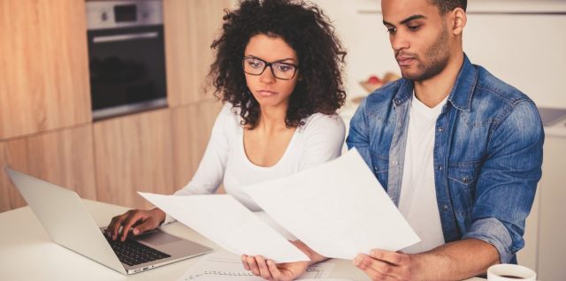 Deux associés examinent des documents immobiliers autour d’une table avant un achat à plusieurs.
